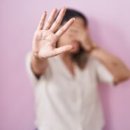 Blonde woman standing over pink background covering eyes with hands and doing stop gesture with sad and fear expression. embarrassed and negative concept.